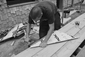 Gros plan sur les mains d'un couvreur utilisant une pince à border manuelle pour plier une tôle en zinc.