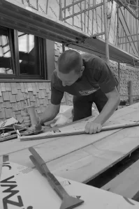 Un couvreur utilise une plieuse manuelle pour façonner une pièce de zinc sur un chantier en rénovation.